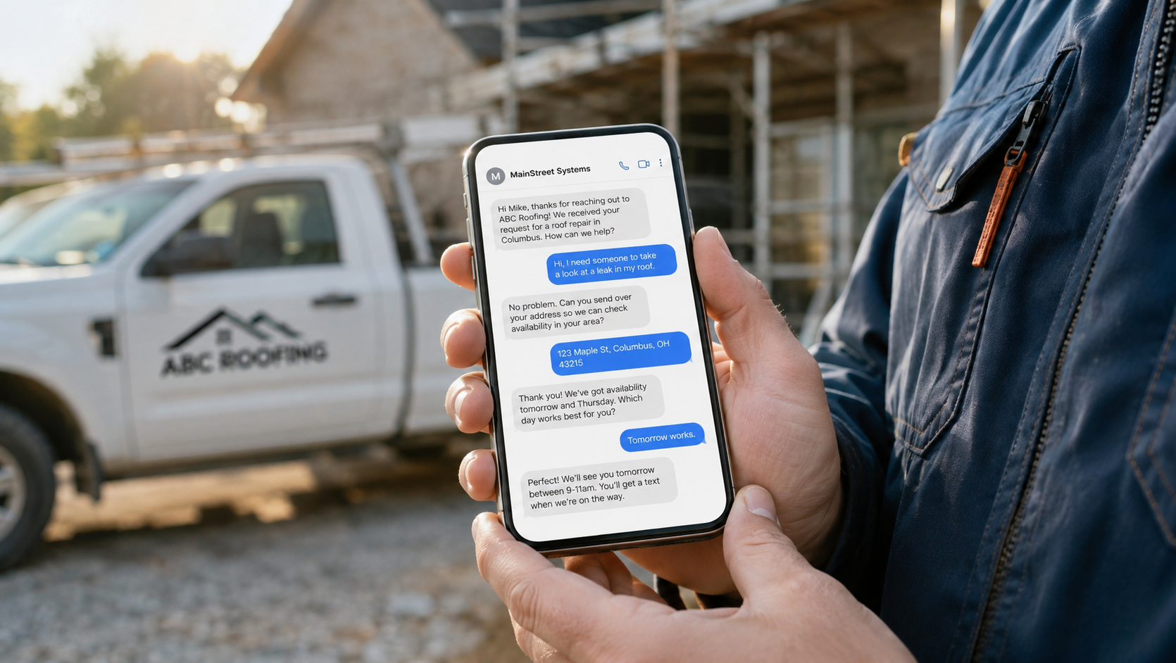 Contractor holding a phone showing an automated MainStreet Systems text conversation booking a roof repair, work truck in the background